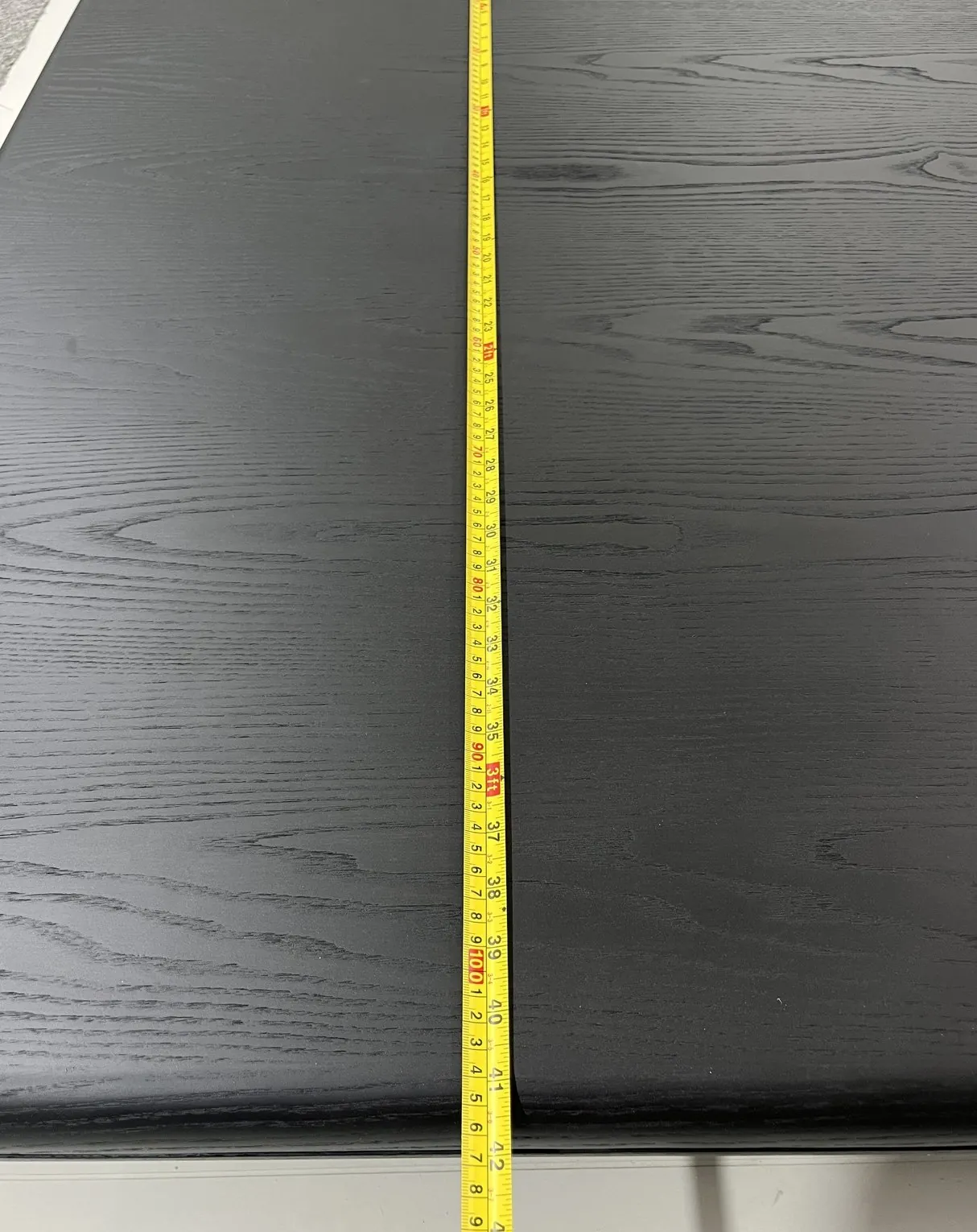 Tape measure placed across a dark tabletop in a separate anonymized product QC record.