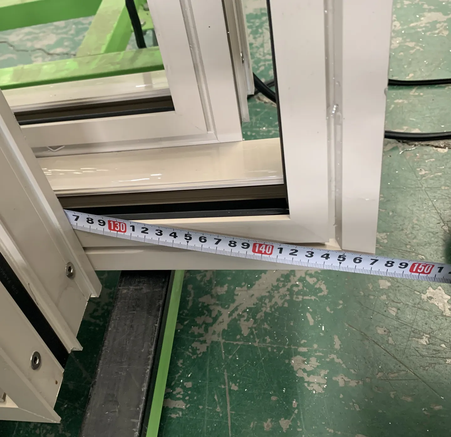 Anonymized close view of a measuring tape used on a window unit during factory QC.